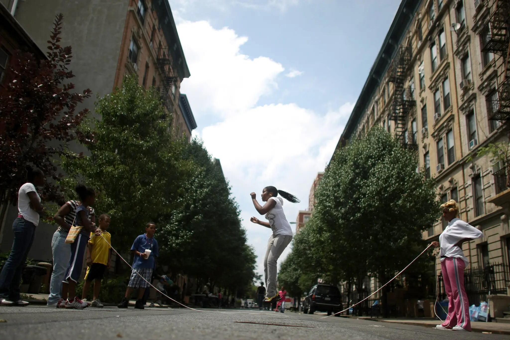 Student jumping over a jump rope on an open New York City street during recess time